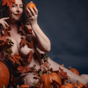 gretel, naked, wrapped in fall leaves holding a pumpkin