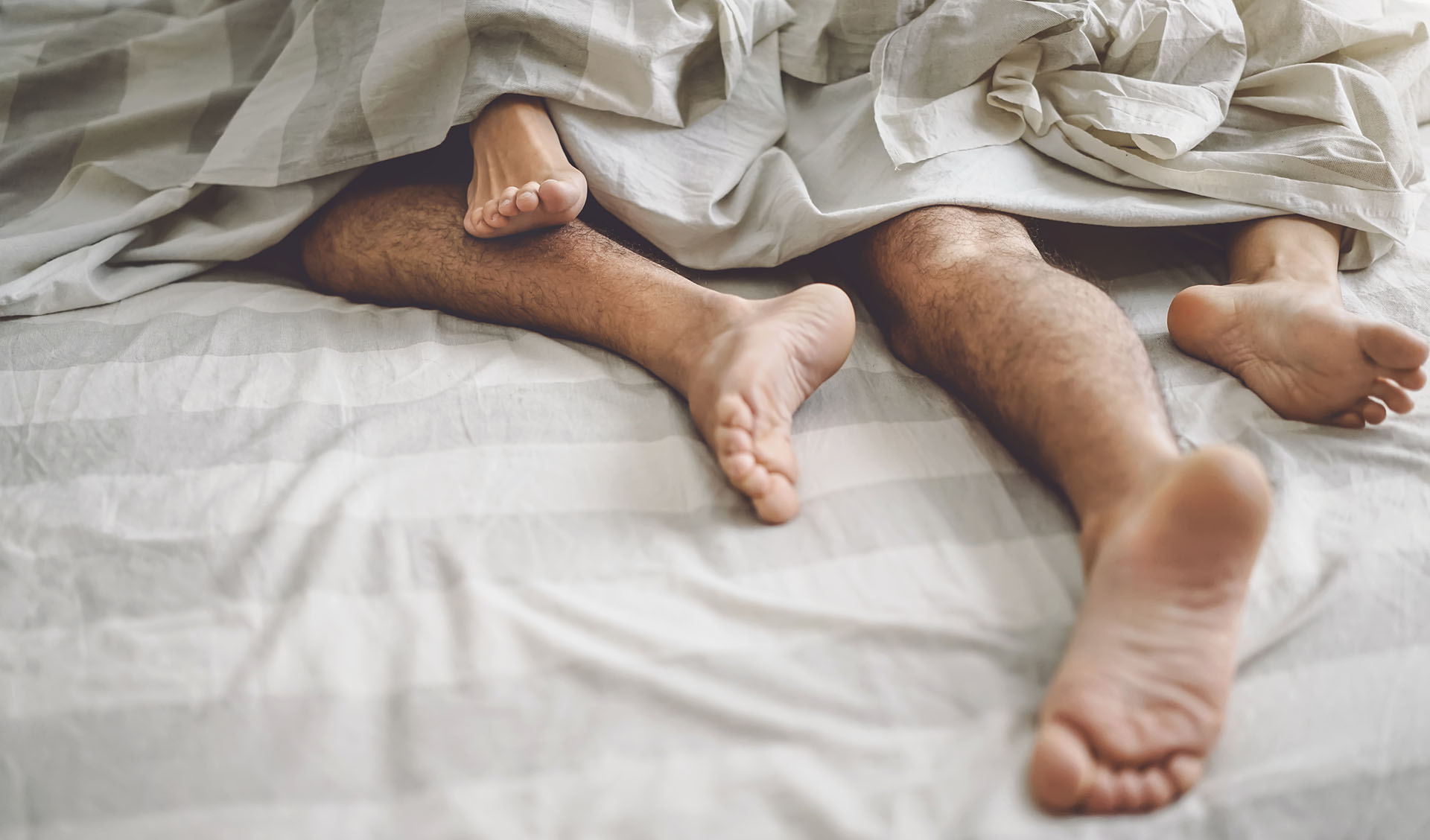 man and women in bed feet entangled